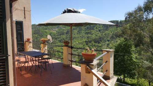 CamposascoRural House Rondini的阳台配有桌子和雨伞。