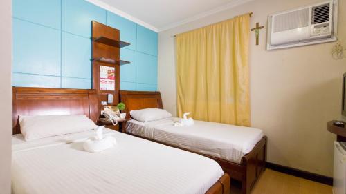 伊洛伊洛卢尔德多米特尔旅馆的一间设有两张床的客房,墙上有一个十字架