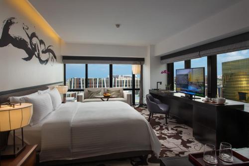 马尼拉City of Dreams - Nobu Hotel Manila的一间卧室配有一张大床和一张书桌及电视