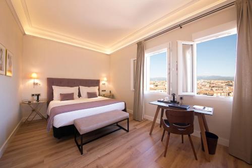 塞哥维亚Real Segovia by Recordis Hotels的酒店客房设有一张床、一张书桌和窗户。