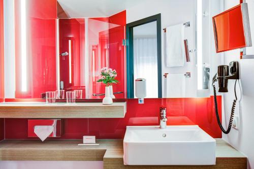 罗斯托克罗斯托克城际酒店 的红色的浴室设有水槽和镜子
