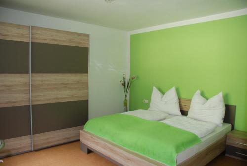HüttschlagFerienwohnung Kendler的绿色卧室配有带白色枕头的床