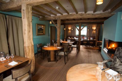 CoddingtonCock O' Barton的餐厅设有木桌、椅子和壁炉