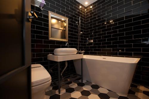 昌原市格雷酒店的黑色瓷砖浴室设有卫生间和水槽