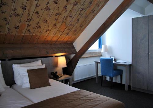 Veenhuizen苦与甜酒店的一间卧室配有一张床和一张带蓝椅的书桌