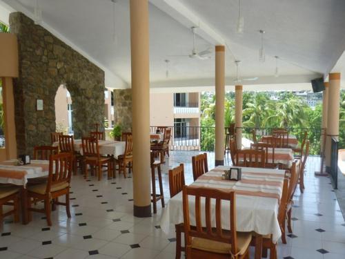 埃斯孔迪多港Hotel Barlovento的一间带木桌椅的餐厅和一间房间