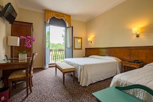 摩德纳城堡酒店的酒店客房设有两张床、一张书桌和一个窗户。