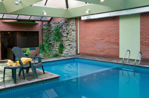 马德普拉塔卓越公寓酒店的游泳池旁设有桌子和椅子