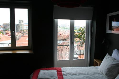 波尔图2U Oporto Urban Stays的一间卧室设有一张床和两个美景窗户。