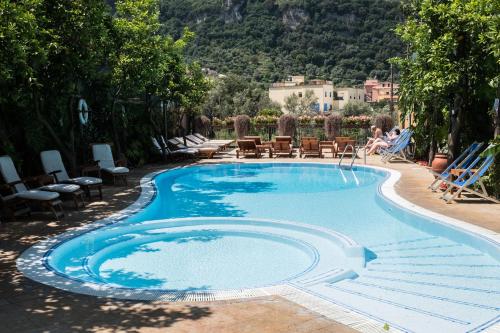 索伦托维拉焦佛得住宿酒店的游泳池旁设有椅子和椅子上的女人