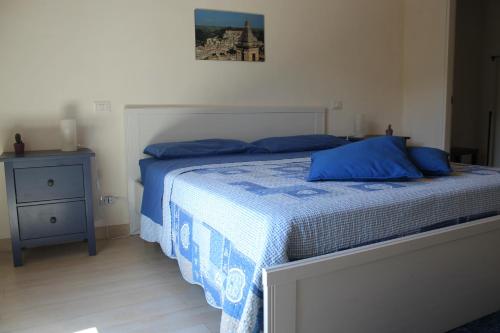 拉古萨Amaca Iblea的一间卧室配有一张带蓝色床单的床和床头柜。
