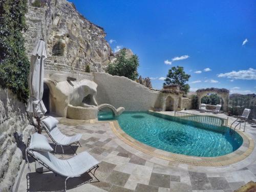 于尔居普尤纳克埃夫勒里卡帕多西亚酒店的一个带两把草坪椅的游泳池和一个带游泳池的庭院