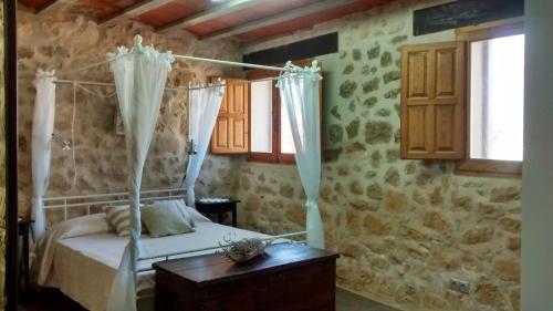 阿尔内斯Casa De Vacances La Vella Era的一间卧室配有一张带窗帘和桌子的床
