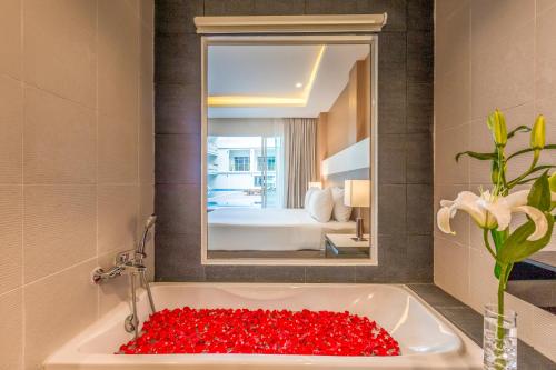 卡伦海滩Chanalai Hillside Resort, Karon Beach的一间设有装满红玫瑰的浴缸的浴室