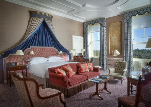 塔普洛Cliveden House - an Iconic Luxury Hotel的一间卧室配有一张大床和一张红色的沙发