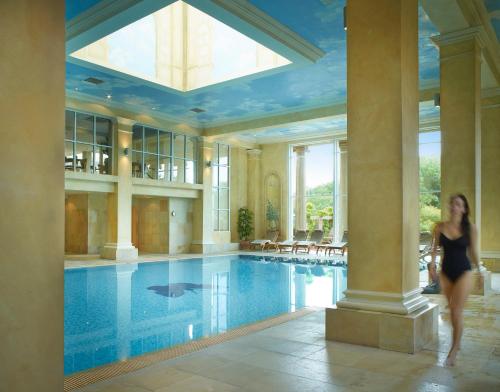 新米尔顿Chewton Glen Hotel - an Iconic Luxury Hotel的一位在游泳池前行走的女人