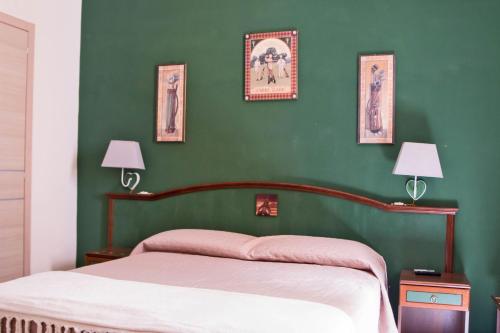 圣塞韦罗B&B Via Roma的一间卧室设有绿墙、一张床和两盏灯。