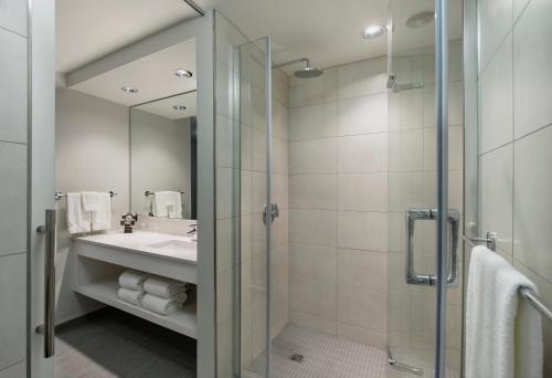 温尼伯诺伍德酒店的带淋浴、盥洗盆和镜子的浴室