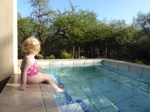玛洛斯帕克Kruger Cottage的坐在游泳池边的小女孩