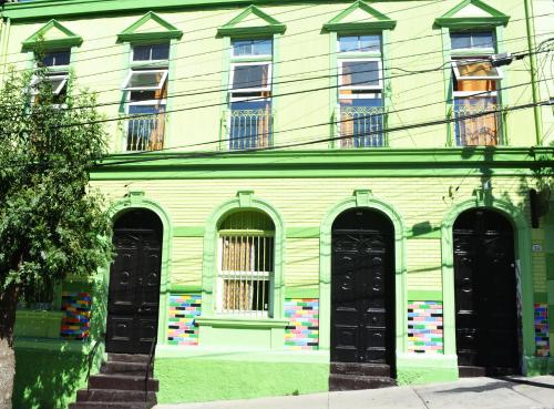 瓦尔帕莱索La Casa Piola的绿色建筑,设有黑色门窗