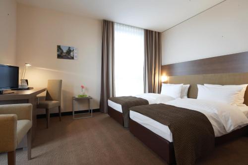曼海姆曼海姆城际酒店的酒店客房设有两张床、一张桌子和一台电视。
