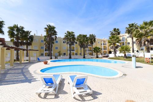 曼塔罗塔Praia da Lota Resort – Beachfront Apartments的一座带两把躺椅的游泳池以及一座建筑