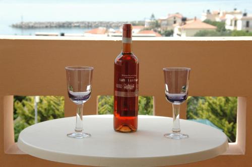 Agia ErmioniToulipa Rooms的一张桌子上放着一瓶葡萄酒,放上两杯