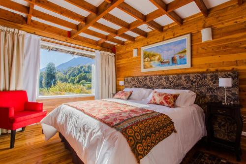 拉安戈斯图拉镇远方宾馆的一间卧室配有一张床、一张红色椅子和一个窗户