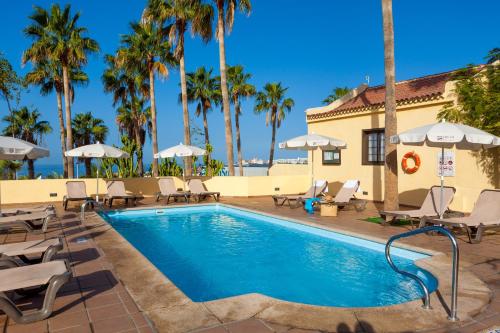 阿德耶阿德赫海岸塔哥洛家庭欢乐酒店的度假村的游泳池配有椅子和遮阳伞