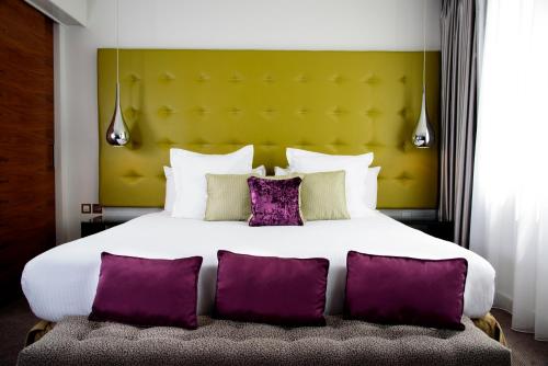 伦敦K西酒店&SPA的一间卧室配有一张带紫色枕头的大床