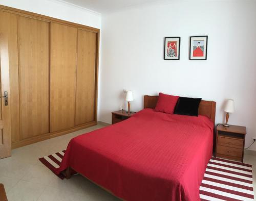 阿尔布费拉Albufeira Bicos Beach Apartment的一间卧室配有一张带红色床罩和木制橱柜的床。