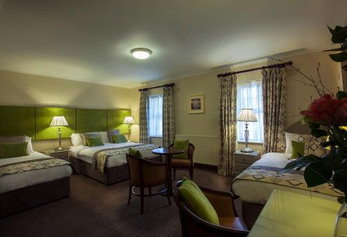 ArvaghBreffni Arms Hotel的酒店客房带两张床和一张桌子以及椅子。