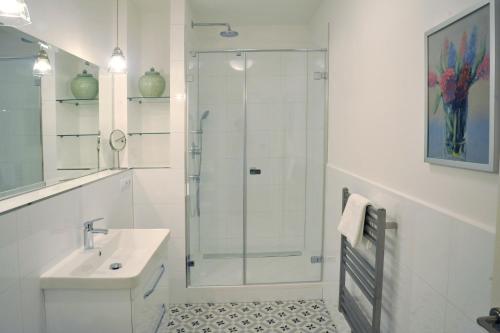 玛丽亚温泉Galerie Suites的带淋浴和盥洗盆的白色浴室
