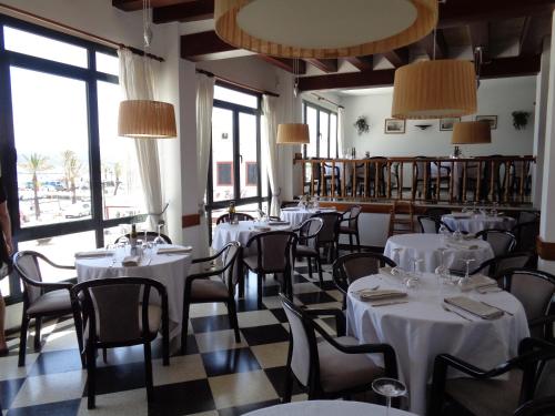 福尔内利斯Hostal S'Algaret的餐厅设有白色的桌椅和大窗户。