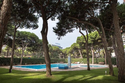 布拉内斯Apartamentos Blanes-Condal Costa Brava的树木繁茂的公园内的游泳池