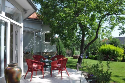 维斯普雷姆Kertes的庭院设有红色椅子、桌子和树