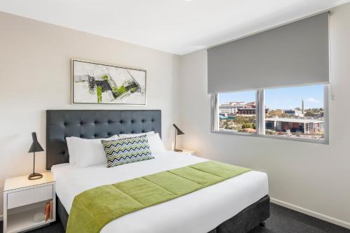 布里斯班Oaks Brisbane Woolloongabba Suites的一间卧室设有一张大床和两个窗户。