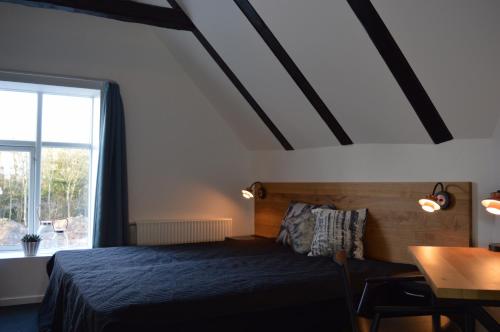 Jægerspris芬霍住宿加早餐旅馆的一间卧室配有一张床、一张桌子和一个窗户。