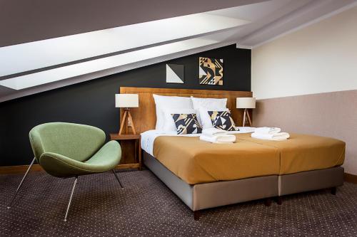 克拉科夫祖利安阿特瑞酒店 的一间卧室配有一张床和一把绿色椅子