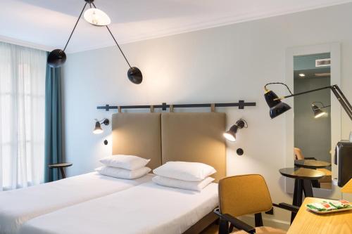 里昂快乐文化思尔可酒店的一间卧室配有带白色枕头和灯的床。