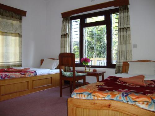 博卡拉新峰会宾馆的一间卧室设有两张床、一把椅子和一个窗户。