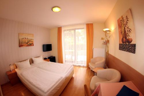 巴特贝林根Hotel Schmid的卧室配有床、椅子和窗户。