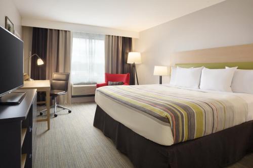 阿什维尔Country Inn & Suites by Radisson Asheville River Arts District的酒店客房设有一张大床和一张书桌。