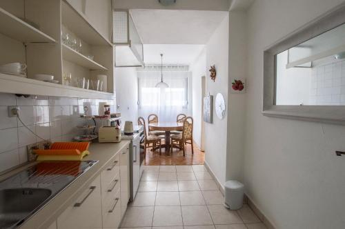 斯普利特Jelena Apartment的一间厨房,配有白色橱柜和一间餐厅