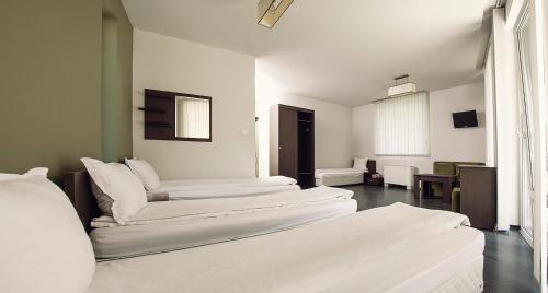 Simitli加利亚纳度假屋的带3张白色床单的床的房间