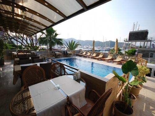 费特希耶多鲁克酒店的一间带桌椅的餐厅和一个游泳池
