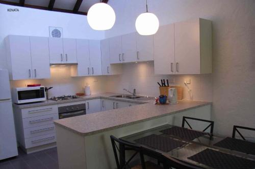 珀斯卡纳达-航道公寓的厨房配有白色橱柜和桌椅