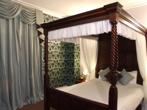 伍尔弗汉普顿伊利别墅酒店的卧室配有带白色床单的天蓬床