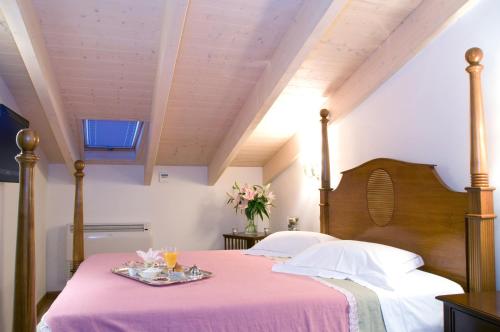 纳弗帕克托斯阿宏提可皮普斯酒店的一间卧室配有一张带粉色毯子的床