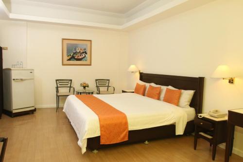 伊洛伊洛港口镇酒店的酒店客房配有一张带橙色枕头的大床